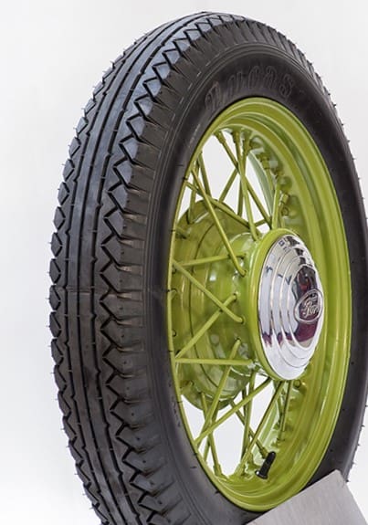 A green tire with a black rim on display, showcasing 525 by 550 18 LUCAS Olympic Tread Blackwall tires.