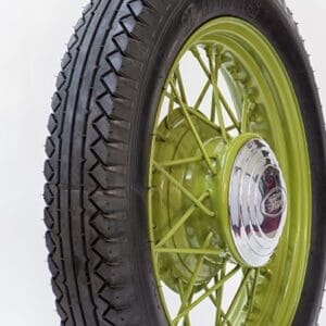 A black rim with a green tire on display featuring the 525 by 550 17 LUCAS Olympic Tread Blackwall.