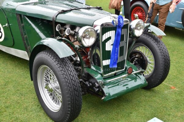 Sentence with product name: Vintage green racing car with number 2 displayed, parked on grass at a car show, featuring prominent headlights and 550-18 PIRELLI STELLA BIANCA wheels.