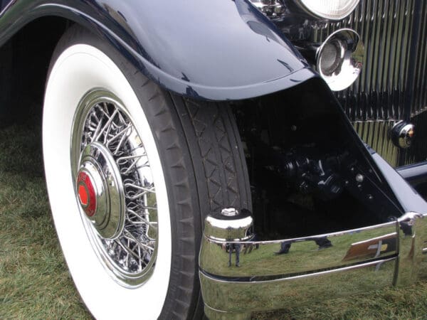 Close-up of a vintage Bedford car showing its detailed Bedford 750-17 3-3/4' WW wheel with spokes, and shiny chrome bumper and grille.